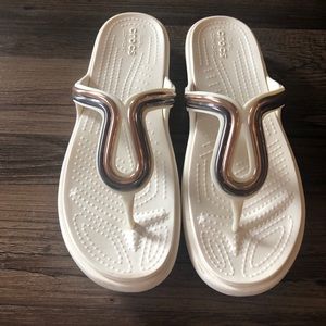 White and bronze Crocs flip flops